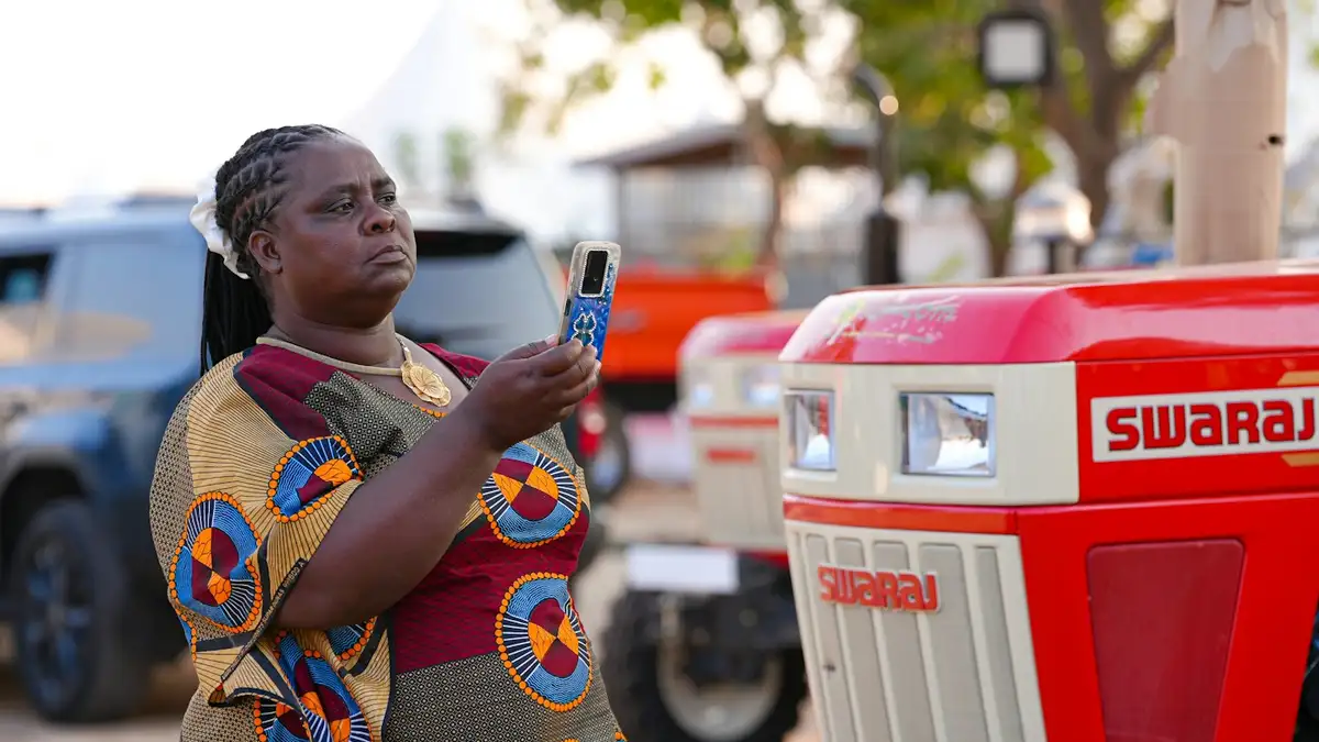 Productrice consultant son téléphone devant des tracteurs